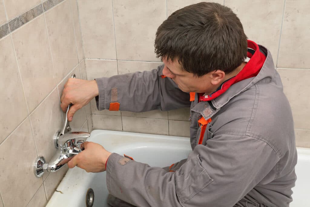 Plumber working on bath faucet